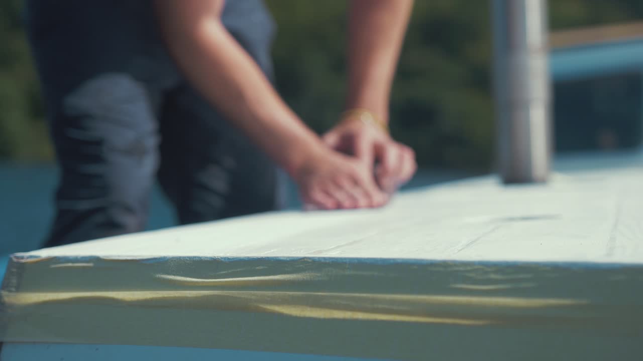 крупным планом руки на наждачной бумаге, шлифующие крышу деревянной лодки