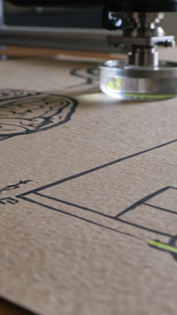Vídeo vertical: Motor iniciando, movendo a cabeça ao longo de um trilho sobre papel em uma bancada, alinhando-se a uma linha verde.