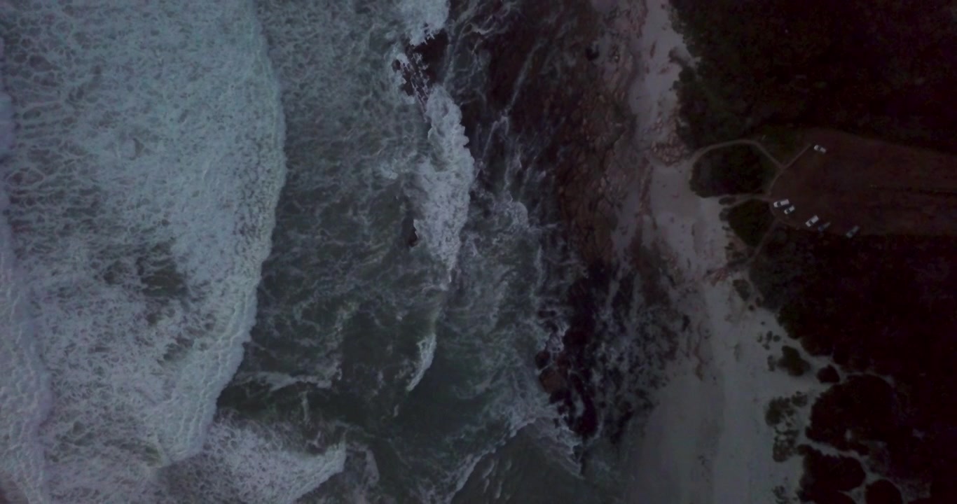 Aerial View of Ocean Waves Crashing Against Rocky Shoreline