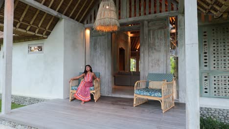 young asian model sitting in a bohemian patio chair at a luxury villa in bali indonesia