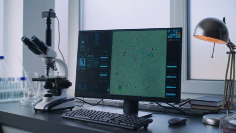 estación de trabajo de laboratorio con microscopio y pantalla de computadora que muestra la muestra celular