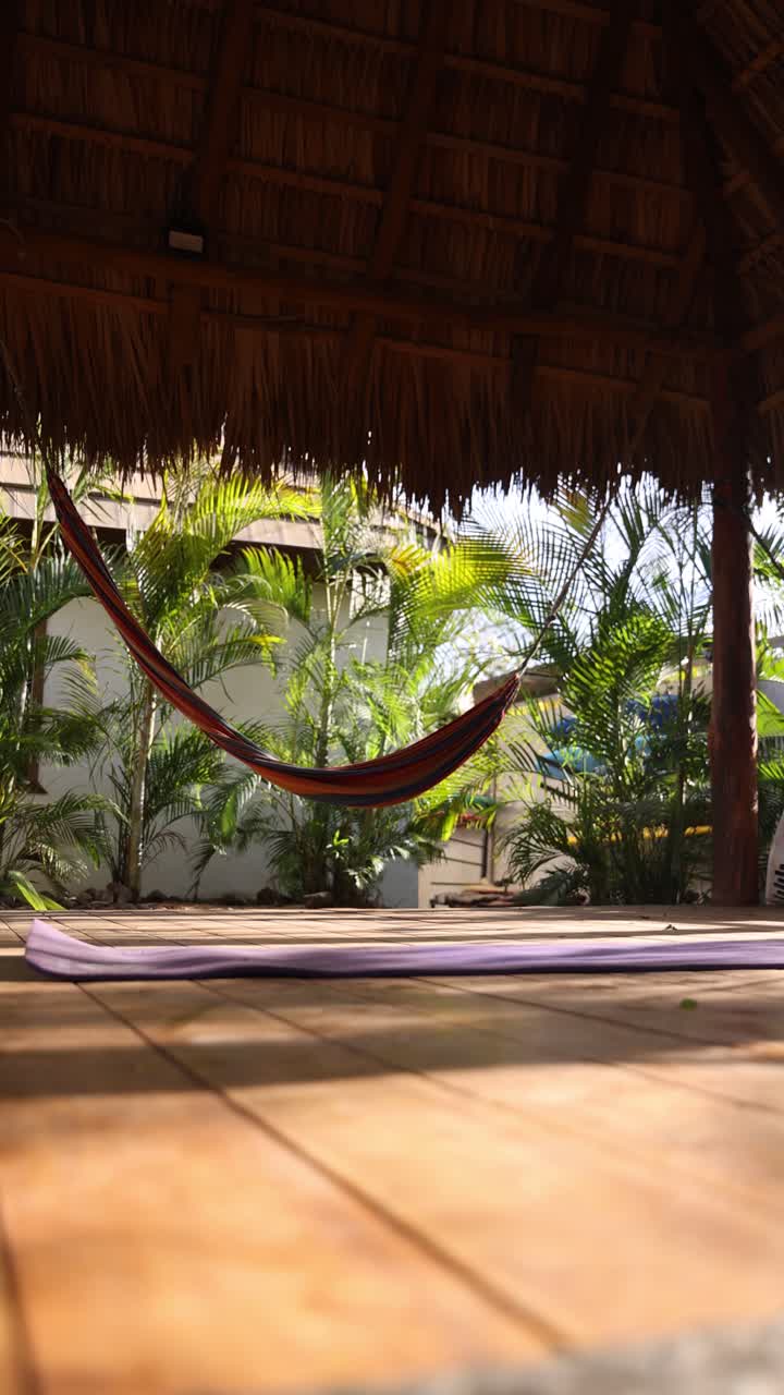 Relaxation and wellness concept with yoga mat and hammock under a thatched roof in tropical paradise