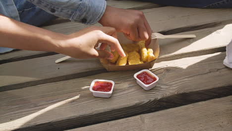 amigos compartiendo comida y mojando nuggets de pollo en ketchup