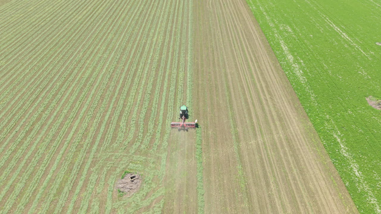 Aerial and ground-level footage of a modern agricultural tractor driving across a green wheat field in rural Bulgaria during spring