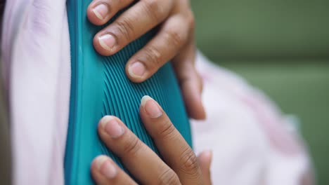 close-up of hands holding a hot water bottle for comfort