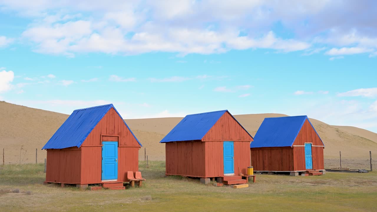 Colorful wooden guesthouses at a tourist camp stand in the arid landscape of remote western Mongolia, near Durgun Nuur lake. A unique lodging destination for local and foreign travelers