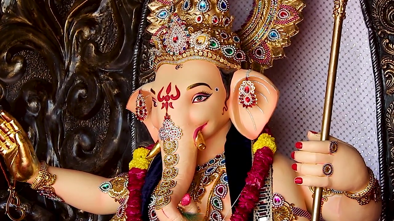 Primo piano del volto di un idolo di Ganesha che mostra gioielli con corona d'oro e dettagli della proboscide durante il festival di Ganesh Chaturthi in India