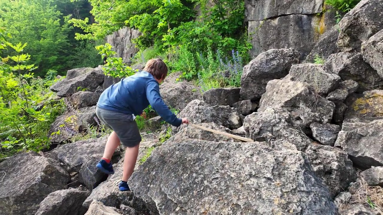 Boy hiking and climbing a rocky trail in Rattlesnake Point Conservation Area in Ontario, Canada