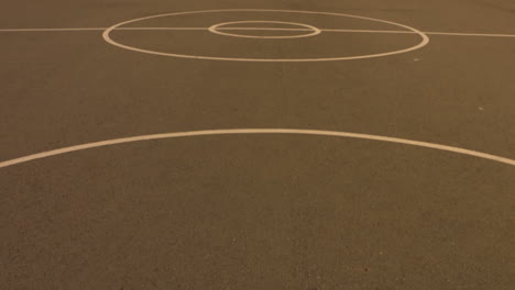 pan up to reveal an empty, outdoor basketball court in the early morning sun