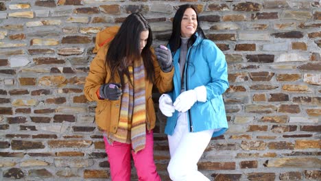 cute twins in winter coats leaning on wall