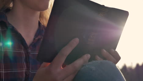 close up of a girl reading the bible in a forest on a sunny day