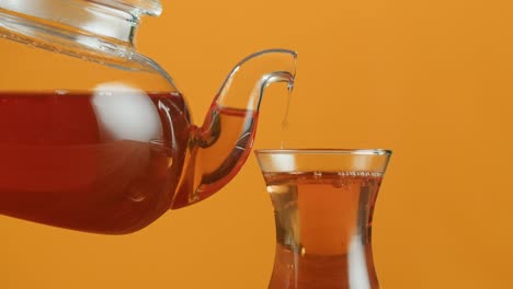 pouring tea from teapot into glass