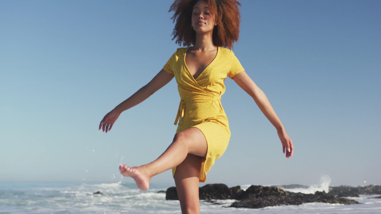 African American woman playing with water at the beach