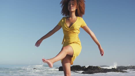 african american woman playing with water at the beach