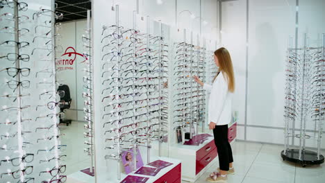 woman choosing eyeglasses in optical store. young business woman choosing glasses at optics store