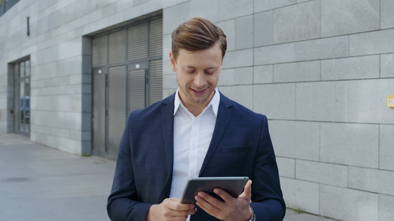hombre de negocios usando tableta digital en la calle. trabajador celebrando la victoria afuera