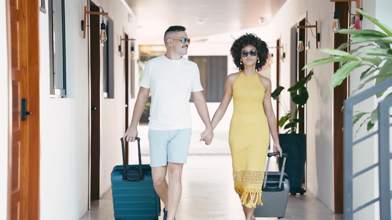 Happy Couple Walking Hand in Hand with Luggage in Hotel Hallway