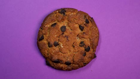 una galleta de chocolate en primer plano, una foto macro, girando lentamente sobre un fondo púrpura giratorio.