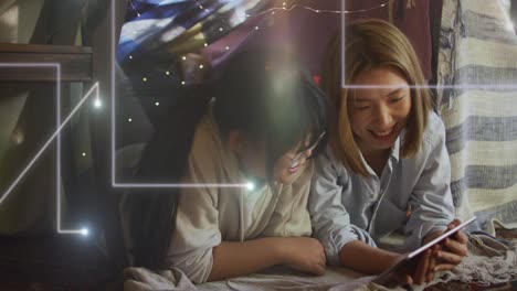 Animation-of-lights-falling-over-happy-asian-mother-and-daughter-using-tablet