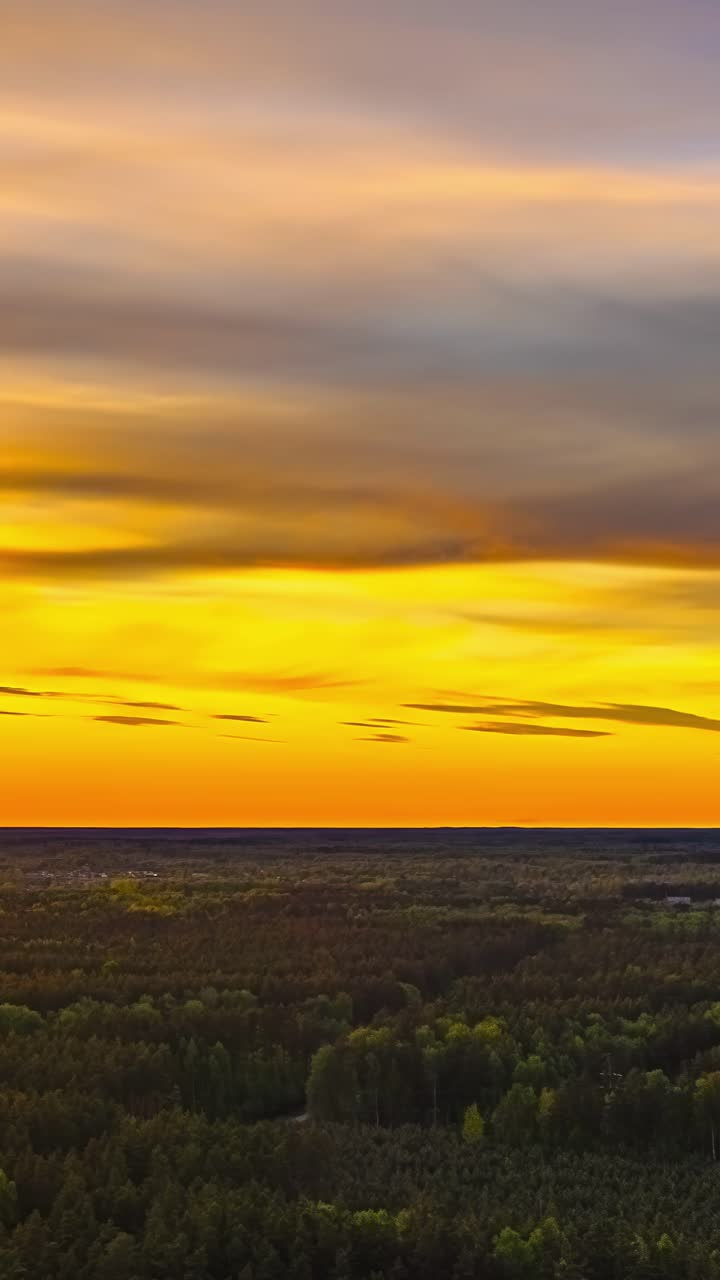 Dramatic sunset sky with dark silhouetted hills as glowing golden light fading into deep red over forest, ideal as visual background, vertical static