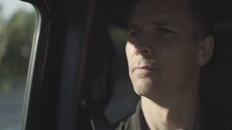 Middle aged man riding in a car stares ahead as the car drives down the road
