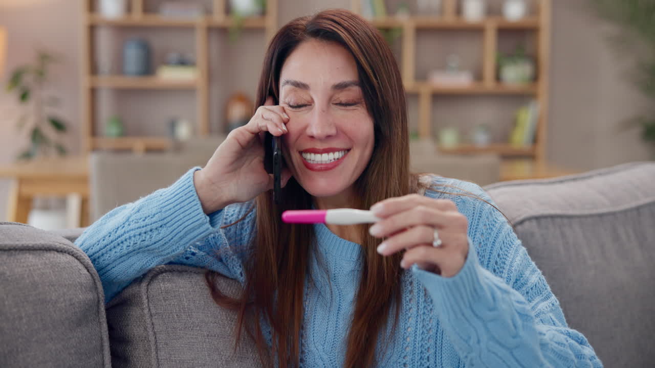 Mujer al teléfono con una prueba de embarazo positiva