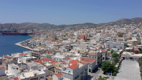 Slow-panoramic-drone-panning-shot-of-Ermoupoli-city-in-Syros-island,-Greece-during-sunrise