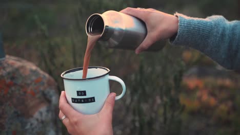 Zeitlupenaufnahmen-Einer-Frau,-Die-Sich-Beim-Camping-Eine-Tasse-Heiße-Schokolade-Einschenkt