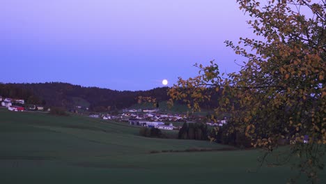 moon rising over a romantic village in bavaria germany on a autumn evening