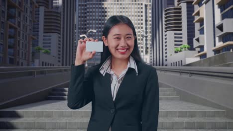도시 에서 서 있는 동안  카드 를 들고 미소 를 지는 아시아 의 사업가
