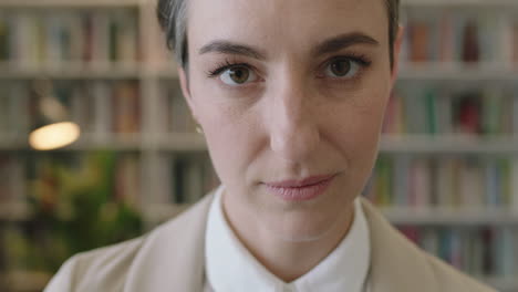 close-up-porträt einer jungen schönen frau, die in die kamera schaut, nachdenklich fokussiert und einen stilvollen anzug im hintergrund des bücherregals der bibliothek trägt