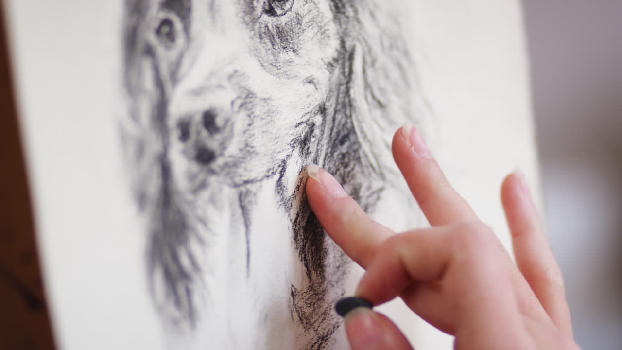 primer plano del artista sentado en el caballete dibujando una imagen de perro en carbón