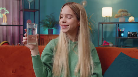 thirsty caucasian woman sitting at home holding glass of natural aqua make sips drinking still water