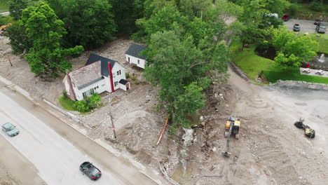 aftermath of flood damage: aerial view of single-family home with excavators, vt