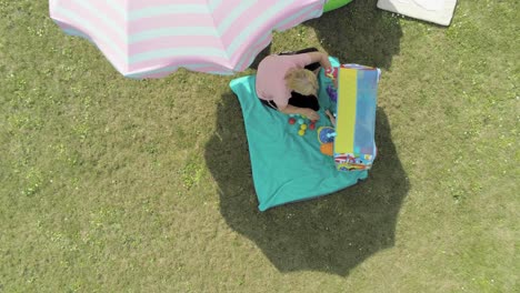 looking down on a mother playing with her child under an umbrella in the backyard, aerial