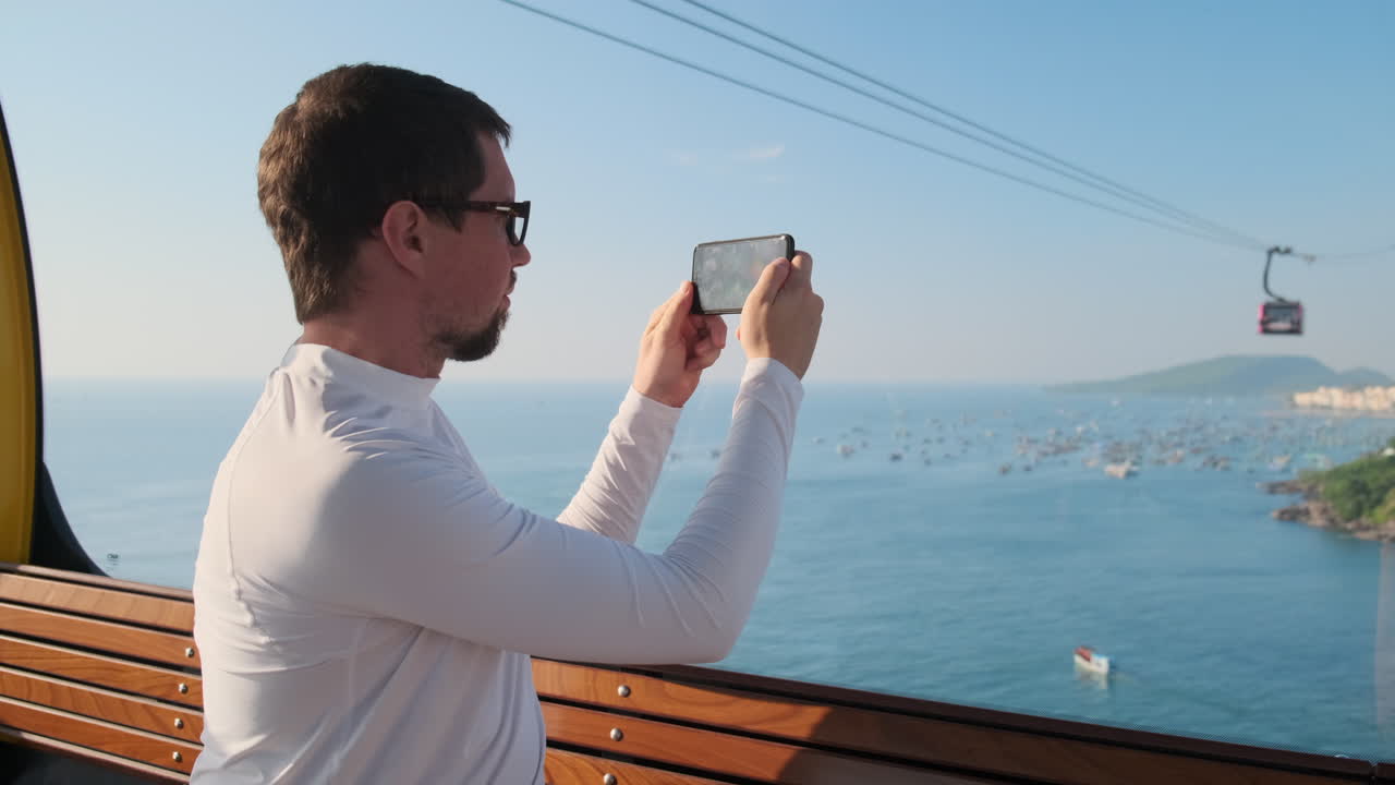 hombre tomando una foto de la vista del mar desde el teleférico
