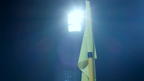 corner flag post blown by wind on soccer stadium at night, stadium lights in the background