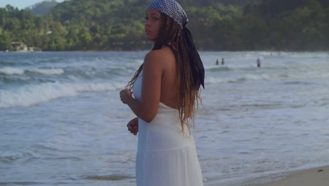 Junge-Frau-Am-Strand-In-Einem-Fließenden-Weißen-Kleid,-Das-Die-Wellen-Genießt