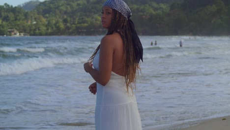 mujer joven en la playa con un vestido blanco que fluye disfrutando de las olas