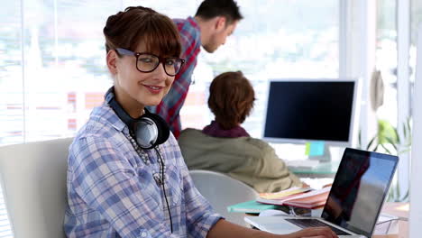 Designer-working-on-her-laptop-and-looking-at-camera