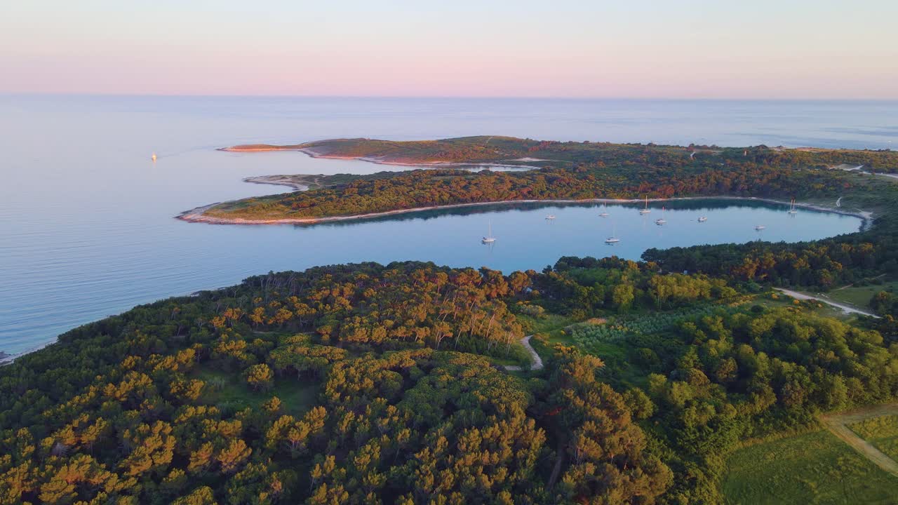 Nesta impressionante vista de drone de uma ilha artisticamente posicionada no coração de um oceano azul deslumbrante, alguns navios podem ser avistados.