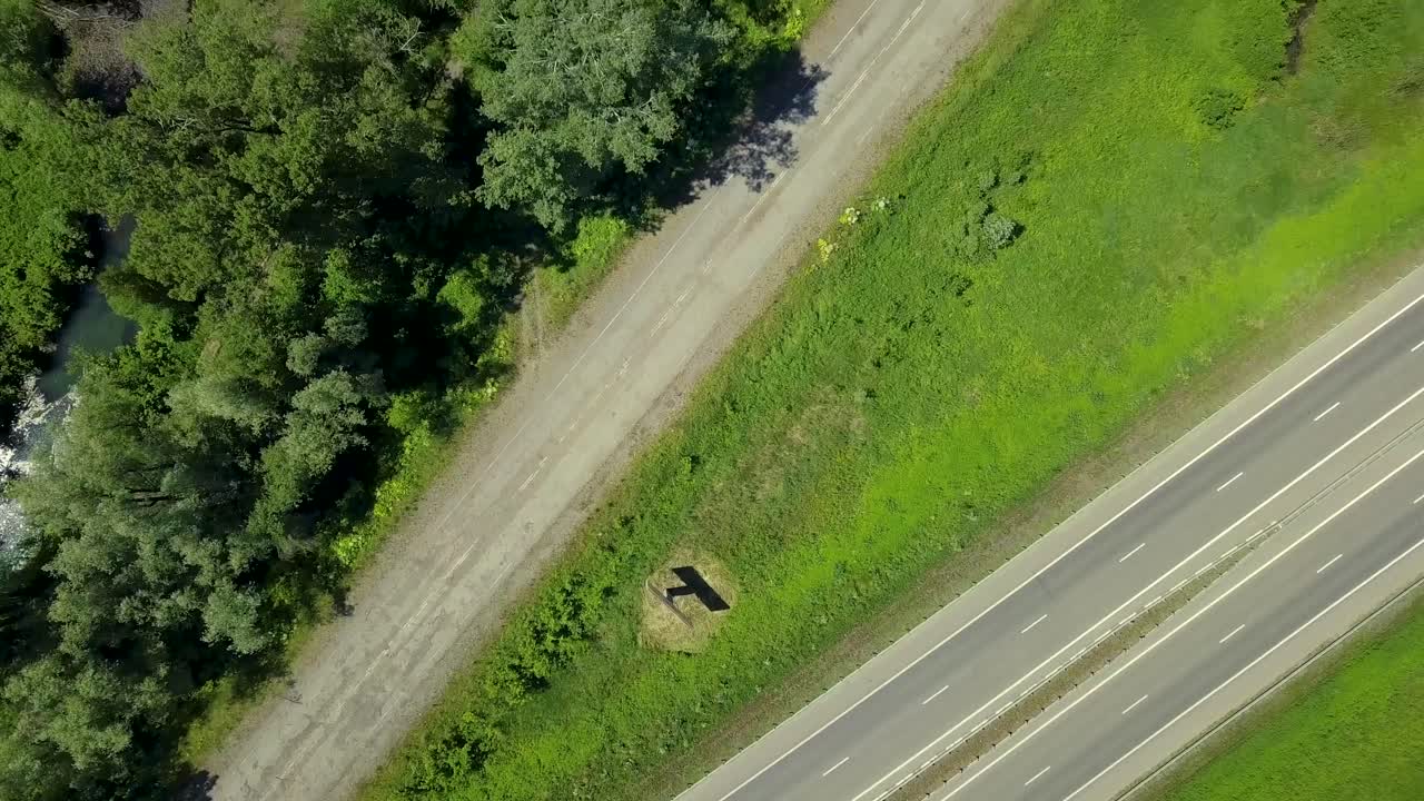 고속도로와 숲 위를 날아다니는 항공기 태양의 빛은 수직으로 아래로 보입니다