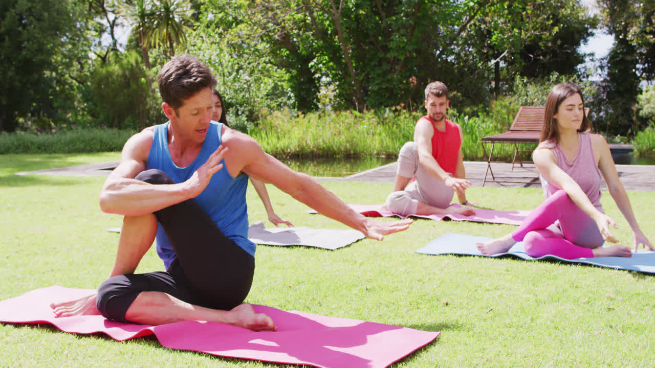 grupo diverso de hombres y mujeres practicando yoga sentados en esteras en un parque soleado