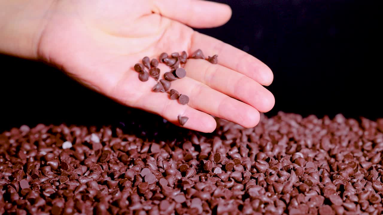 A hand gradually releases chocolate chips