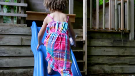 niña jugando en el tobogán en el patio trasero 4k