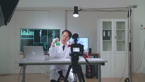 young asian male research scientist holding glass test tube and speaking to the camera with professional lighting