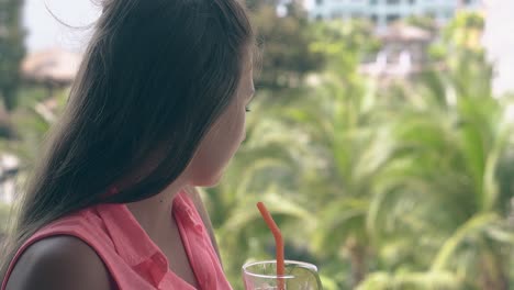 girl drinks cocktail enjoys beautiful view on tall green palms