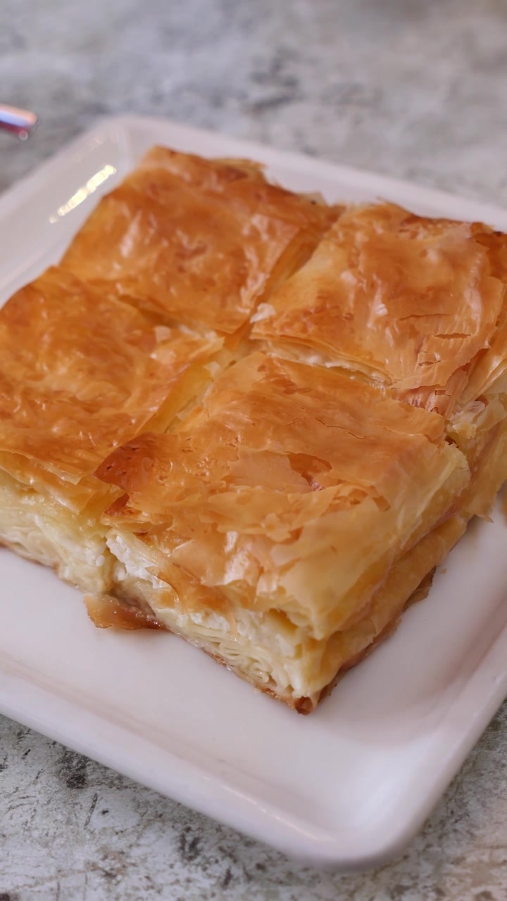 Primo piano di un pezzo di torta salata greca tradizionale al formaggio su un piatto