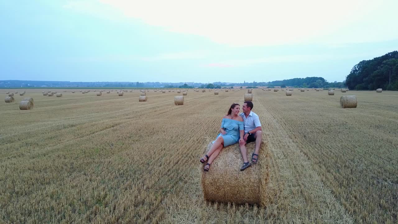 Couple Relaxing On A Field With Hay Bales. Couple walking together through summer harvested field