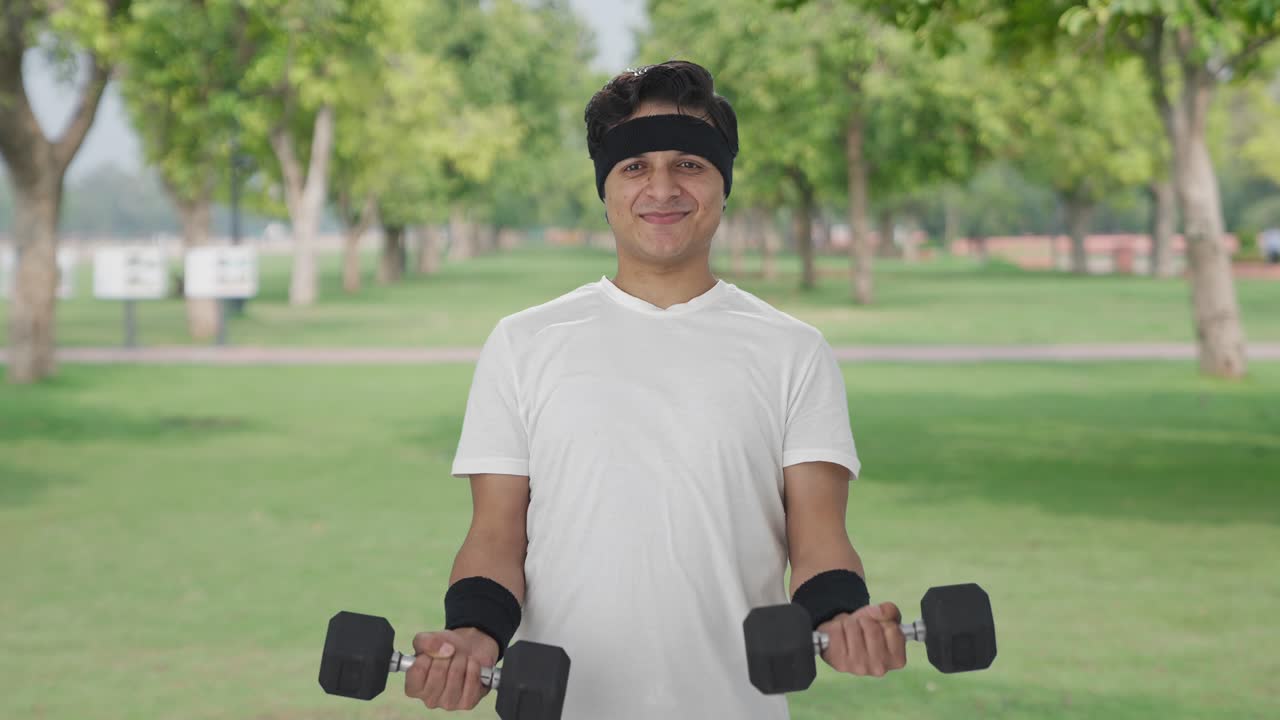 무거운 덤벨을 들어 올리는 행복한 인도인